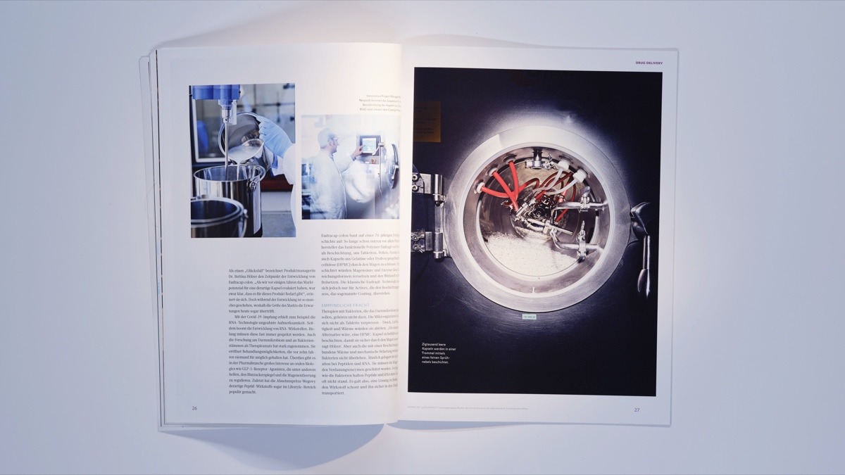 Photographed magazine spread with laboratory process photos and a large image of a stainless-steel coating drum spraying capsules inside a dark chamber. Fotografierte Magazin-Doppelseite mit Laborprozessfotos und einem großformatigen Bild einer Edelstahl-Beschichtungstrommel, die Kapseln in einer dunklen Kammer besprüht. Editorial photography / Editorialfotografie (Evonik Elements, KNSK): Robert Eikelpoth, Studio Eikelpoth, Düsseldorf.